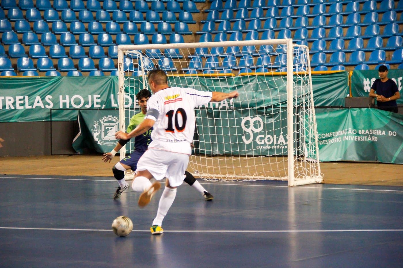 Jogadores durante uma partida de futsal em quadra coberta